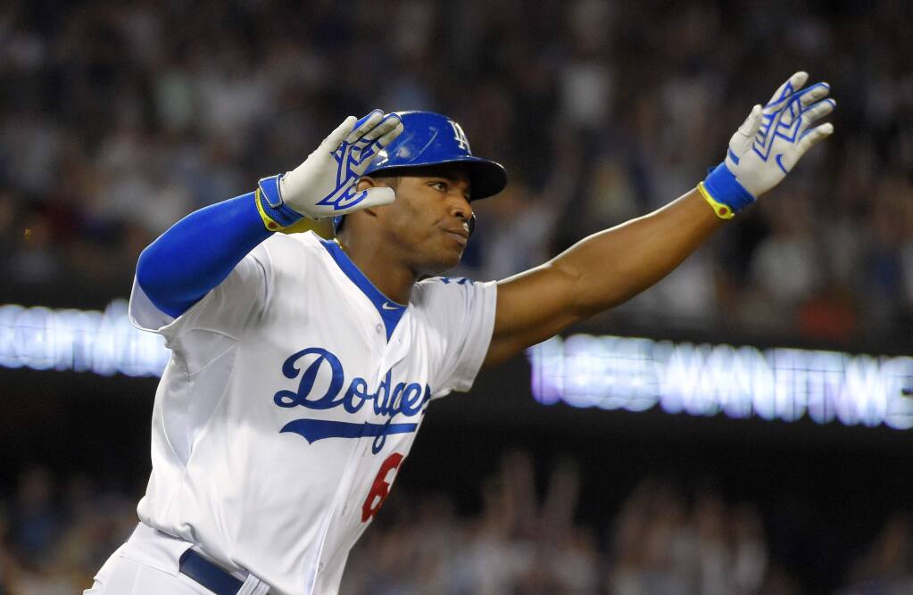 Yasiel Puig of the Los Angeles Dodgers reacts as he hits a RBI