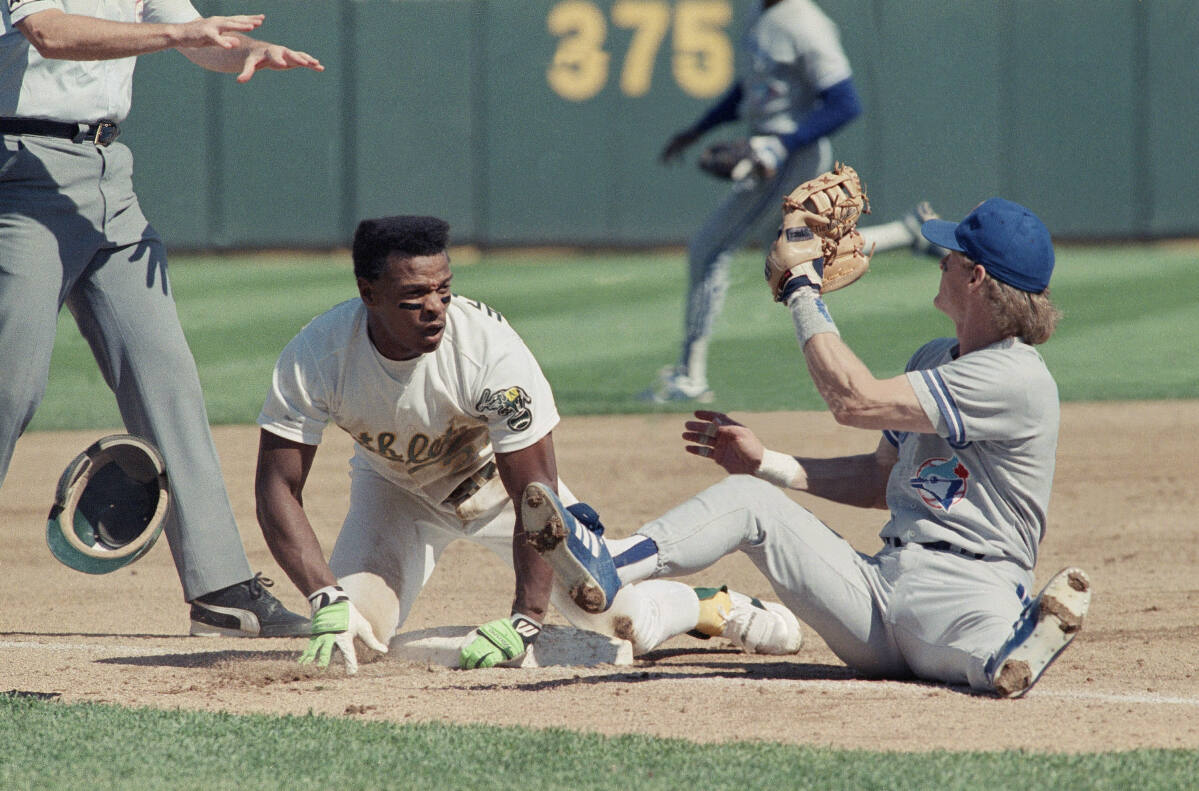 Rickey Henderson slides into home after hitting a home run to