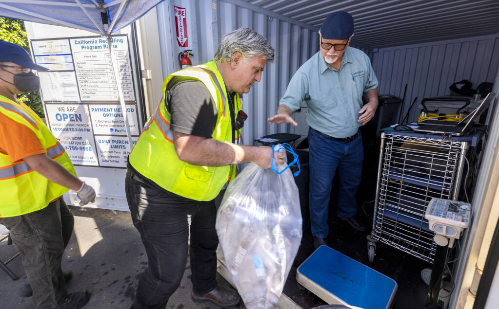 John Santos, left, helps Dennis Blong weigh out bags of plastics for recycling at the new CRV beverage container recycle center at the Community Church of Sebastopol on Thursday, March 31, 2022. (John Burgess/The Press Democrat)