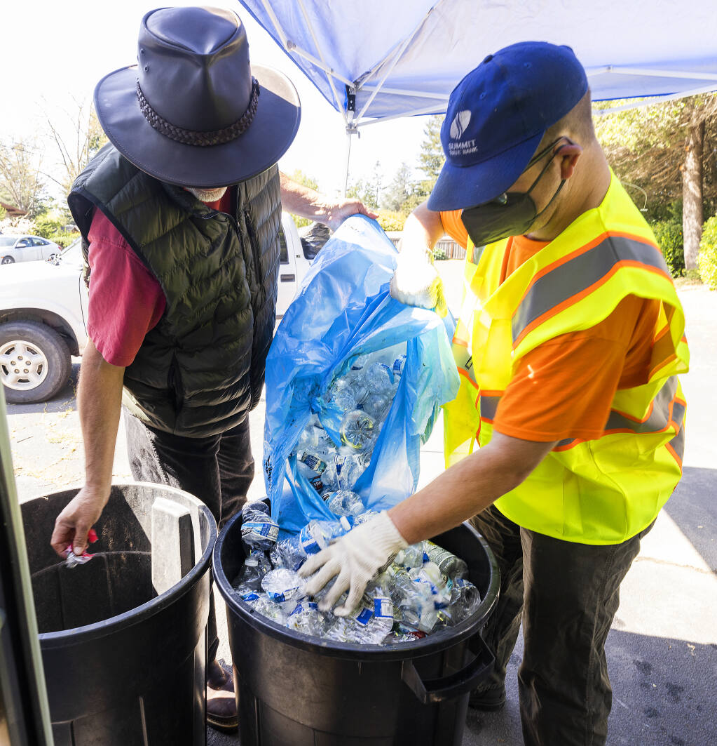 Nathan Morphew, right, helps James Carrigan empty his bags of plastic bottles into a bin at the new CRV beverage container recycle center at the Community Church of Sebastopol on Thursday, March 31, 2022. (John Burgess/The Press Democrat)