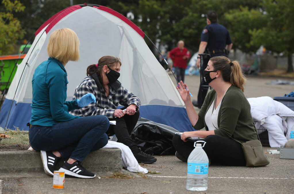 City of Rohnert Park housing administrator Jenna Garcia, left, and homeless services coordinator Emily Quig, right, talk with Michelle Koelblen about shelter options at a homeless encampment at the Roberts Lake Park and Ride lot in Rohnert Park on Friday, September 10, 2021. (Christopher Chung/ The Press Democrat)