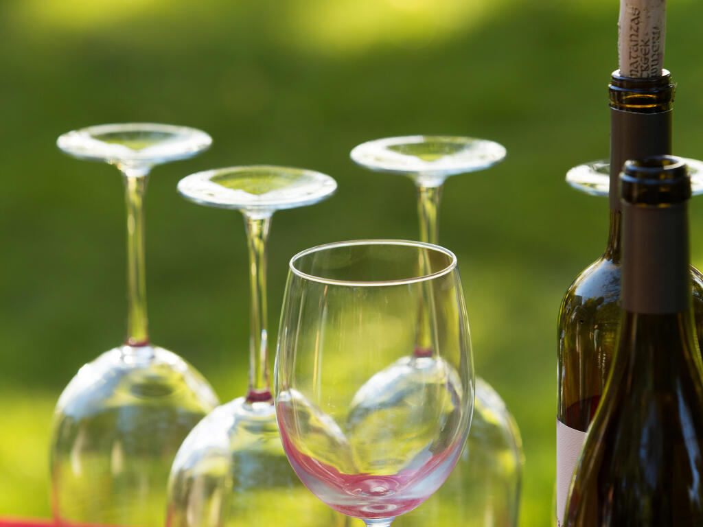 Wines crafted from several varietals are 20% to 30% lower in price than straight varietals, according to Barry Herbst, wine director of Santa Rosa’s Bottle Barn. Wine glasses and bottles populate a table at the Friday Night wine tasting at the Gable Inn's tasting garden. (Gable Inn)