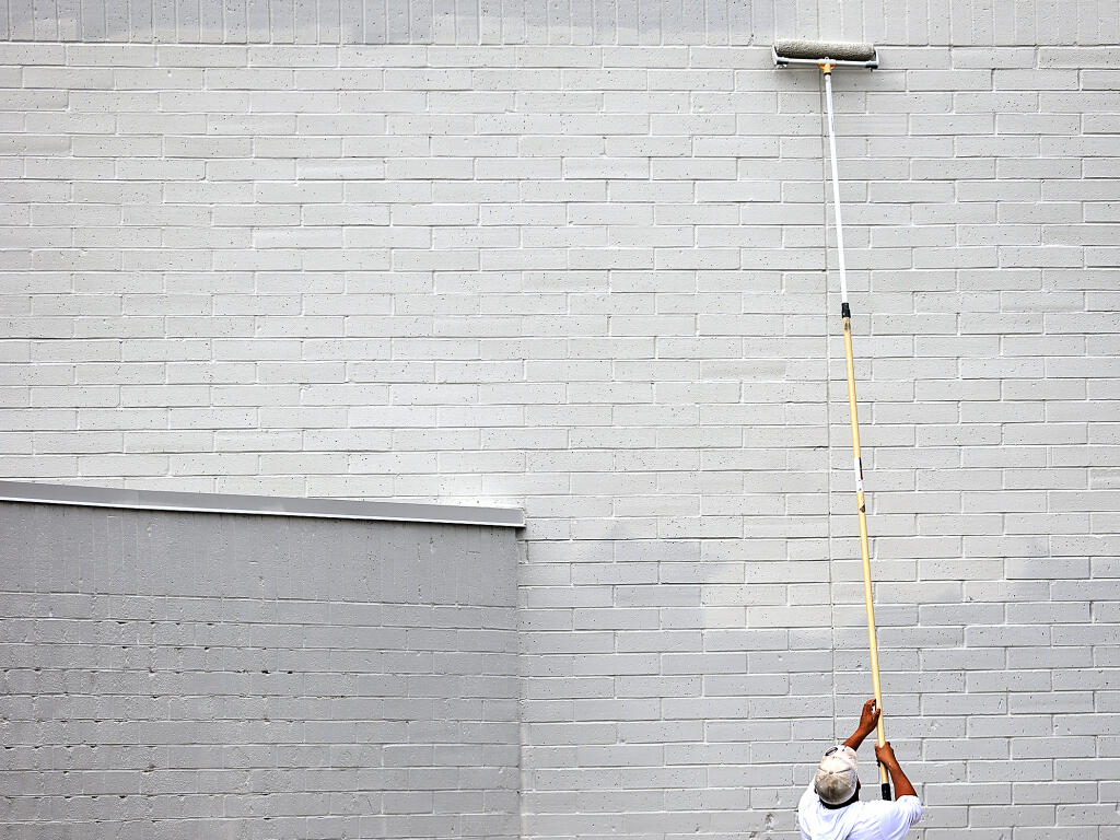 Nate Anderson of Mike Chavez Painting rolls on the final coat of 'repose gray'  to the facade of the Santa Rosa Plaza, Wednesday, Sept. 6, 2023 in Santa Rosa. (Kent Porter / The Press Democrat) 2023