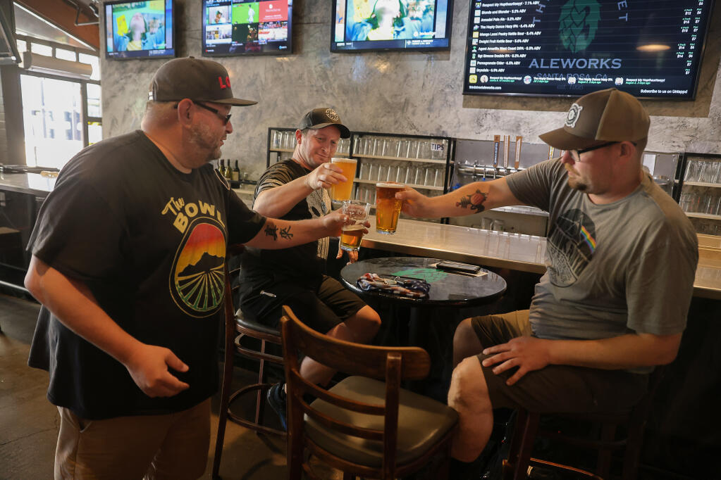 Dwayne Malone, left, Christian Velasquez, and Justin Brown have another round of beer at Third Street Aleworks in Santa Rosa on Monday, June 14, 2021.  The pub will be opening the bar and full capacity indoor seating Tuesday. (Christopher Chung/ The Press Democrat)