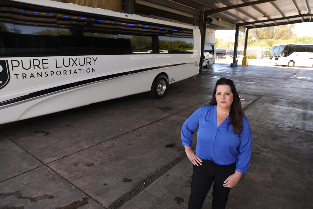 Pure Luxury Transportation owner Jennifer Buffo stands outside one of the shuttle buses in their fleet in Petaluma, Wednesday, June 15, 2022. (Beth Schlanker / The Press Democrat file)