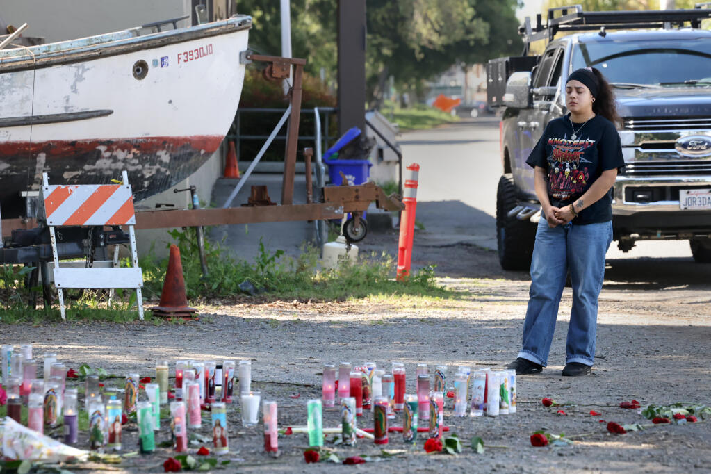 Fernanda Muro pays her respects at a makeshift memorial near the site on Riverside Drive where a 17-year-old girl and 19-year-old woman were found fatally shot Sunday. Photo taken in Napa, Tuesday, April 16, 2024. (Beth Schlanker / The Press Democrat)