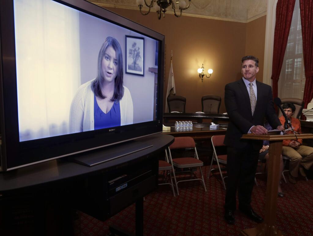 Dan Diaz, the husband of Brittany Maynard, watches a video of his wife, recorded 19 days before her assisted suicide death at the Capitol in Sacramento, Calif., Wednesday March 25, 2015. Maynard was a 29-year-old California woman with brain cancer who moved to Oregon to legally end her life with the help of doctors. Her story drew widespread attention and has since recharged legislative efforts in California and elsewhere to make it legal for terminally ill patients to kill themselves with life-ending drugs. (AP Photo/Rich Pedroncelli)