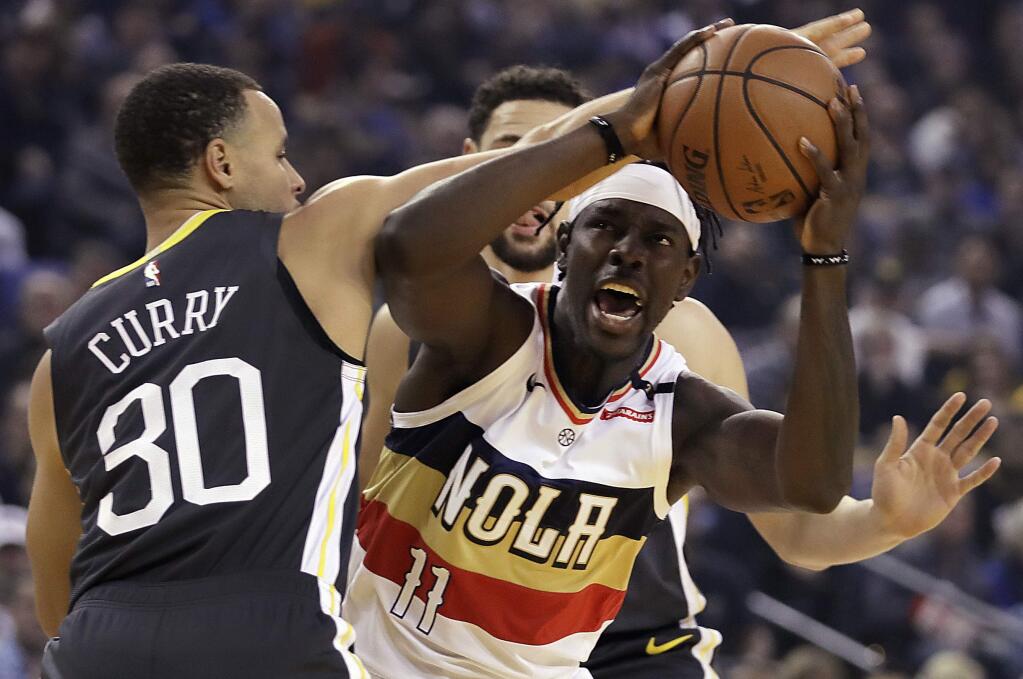The New Orleans Pelicans' Jrue Holiday, right, looks to shoot against the Golden State Warriors' Stephen Curry during the first half Wednesday, Jan. 16, 2019, in Oakland. (AP Photo/Ben Margot)