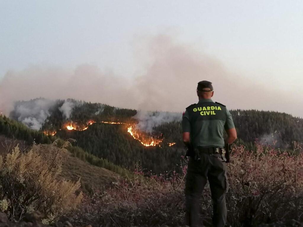 In this photo issued by the Guardia Civil, an officer looks at a forest fire in Gran Canaria, Spain, on Saturday Aug. 11, 2019. Spanish authorities say a wildfire on the Canary Island of Gran Canaria has burned 1,000 hectares (2,470 acres) and has forced the evacuation of 1,000 residents. (Guardia Civil Via AP)