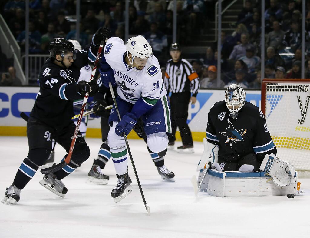 San Jose Sharks goalie Martin Jones (31) blocks a shot from Vancouver Canucks right wing Emerson Etem (26) as Sharks' Dylan DeMelo (74) defends during the second period Thursday, March 31, 2016, in San Jose. (AP Photo/Tony Avelar)