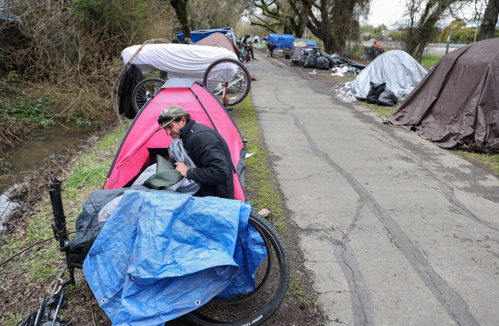 Mike Craig packs up his camp along Joe Rodota Trail as he prepares to move to a managed camp at the Sonoma County administrative campus, Wednesday, March 22, 2023. (Christopher Chung / The Press Democrat)
