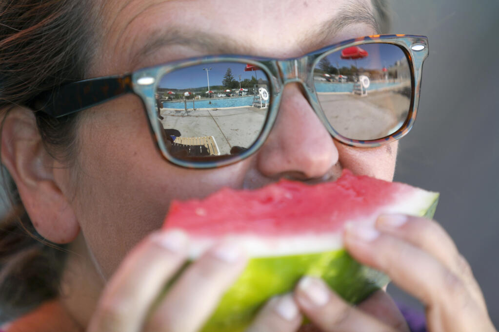 Gail Uselton eats a piece of watermelon while watching her son swim at the city pool in Cloverdale, Calif. on Sunday, Sept. 4, 2022. (Beth Schlanker/The Press Democrat)