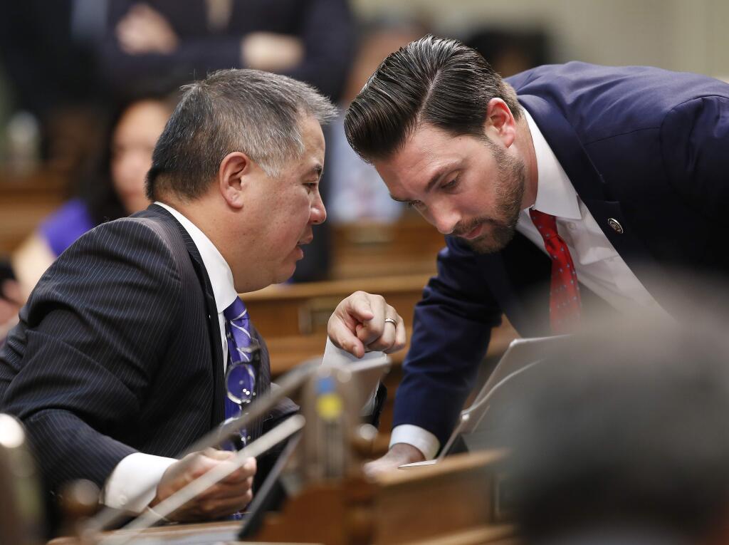 Democratic Assemblyman Phil Ting, of San Francisco, left, and Ian Calderon, of Whittier, right, huddle during the Assembly session Wednesday, May 29, 2019, in Sacramento, Calif. Lawmakers have a Friday May 31 deadline to deal with all legislation in their house of origin. (AP Photo/Rich Pedroncelli)