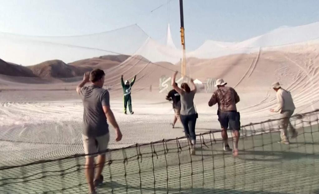 In this image made from a video provided by Mondelez International, Luke Aikins, second from left, celebrates after skydiving without a parachute in Simi Valley, Calif., Saturday, July 30, 2016. After a two-minute freefall, Aikins landed in the 100-by-100-foot net at the Big Sky movie ranch. Aikins made history Saturday when he became the first person to leap without a parachute and land in a net instead. (Mondelez International via AP)