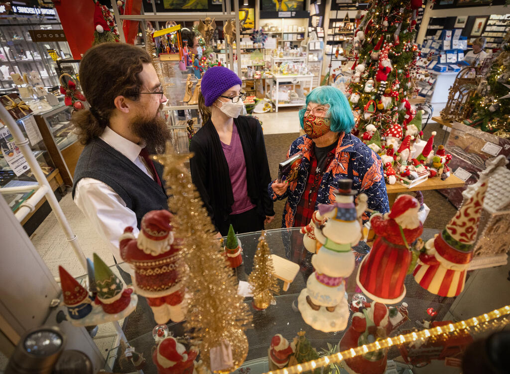 Matthew Sundahl, left, and Melissa Lira help Becky Montgomery find candle bell chimes at Corrick’s Stationery, Gallery & Gifts in Santa Rosa, Wednesday, Dec. 13, 2022. Montgomery and Lira say they have worn masks since the beginning of the pandemic, so new mandates won’t matter (John Burgess/The Press Democrat)