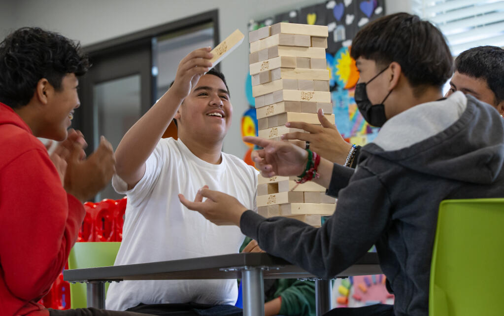 Fabian Hernandez reaches for the top of a Jenga tower to carefully place a block during his move while playing with friends at the Roseland Community Clubhouse of the Boys & Girls Clubs of Sonoma-Marin, Friday June 23, 2023 in Roseland. (Chad Surmick / The Press Democrat)