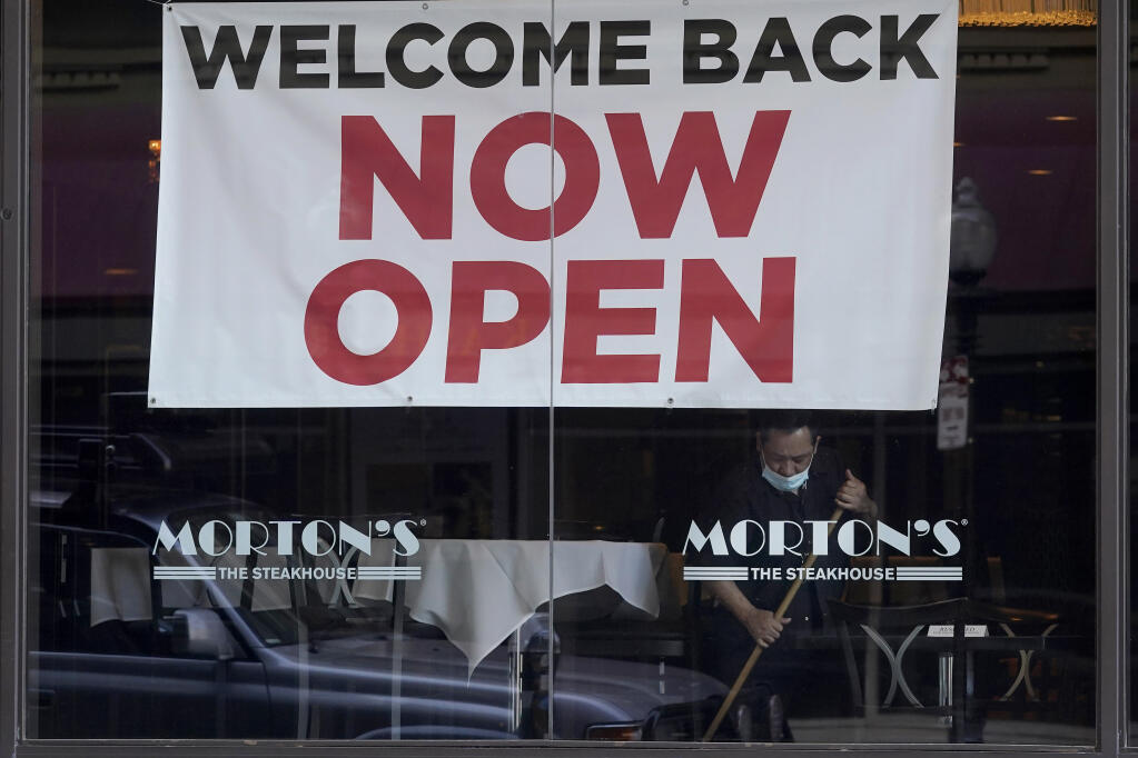 FILE - In this March 4, 2021, file photo, a sign reading "Welcome Back Now Open" is posted on the window of a Morton's Steakhouse restaurant as a man works inside during the coronavirus pandemic in San Francisco. California lost close to 70,000 jobs in January. But new numbers released Friday, March 12, 2021, by the state's Employment Development Department show the unemployment rate declined slightly to 9%. (AP Photo / Jeff Chiu, File)