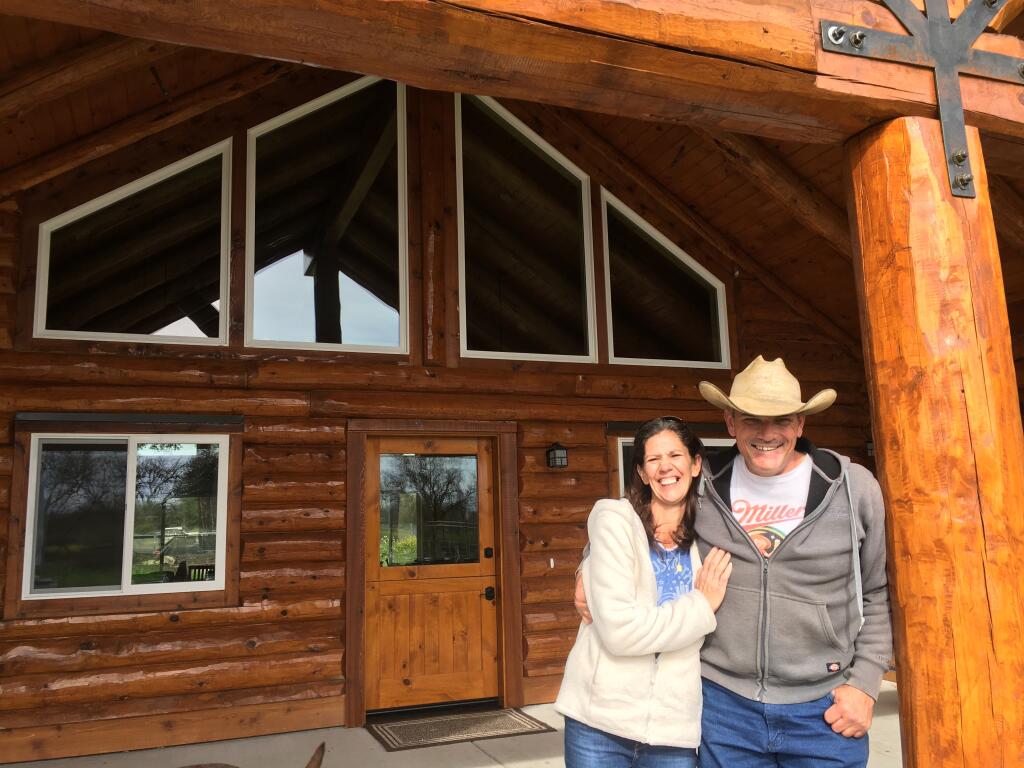 Victoria and Houston Evans are all smiles at the door of the log house recently completed on the site between Highway 101 and north Coffey Lane where the Tubbs fire blew in with deadly effect in October 2017. (Chris Smith / The Press Democrat)