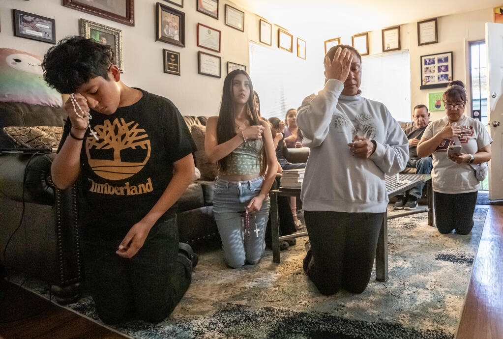 Bryant Alberto Palacios Zuñiga's Brother Alex Martinez, left, god sister Jade Ramirez, mother Naxheli Zuñiga, center, and family friend Martha Solano, right, kneel in the living room of Zuñiga's Coffey Lane home while saying evening prayers before the Virgin Mary for Zuñiga's Son Bryant who went missing April, 2 and later his abandoned car was found near the boarder in Nogales Arizona. Photo taken Thursday, April 17, 2024. (Chad Surmick / The Press Democrat file)
