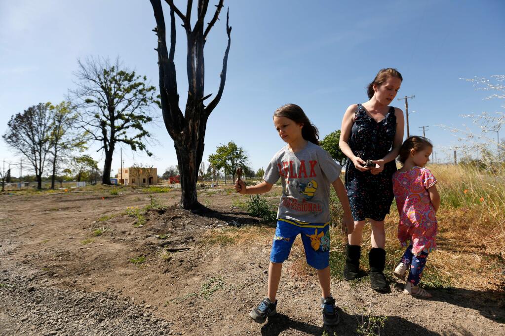 Angel Edwards and her two daughters Arilyn, 6, left, and Anniah, 5, pick up a few remaining items in the cleared lot where their San Sonita Drive home stood before it burned down during the Tubbs fire, in the Coffey Park neighborhood of Santa Rosa, California, on Saturday, May 19, 2018. (Alvin Jornada / The Press Democrat)