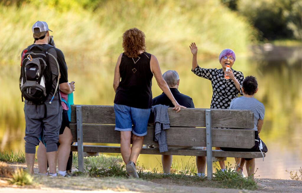 Retired ophthalmologist  Jade Wong gathers a small bench crowd for her 4-minute set of “stealth comedy” at Spring Lake in Santa Rosa, Monday, Sept. 11, 2023. (John Burgess / The Press Democrat)