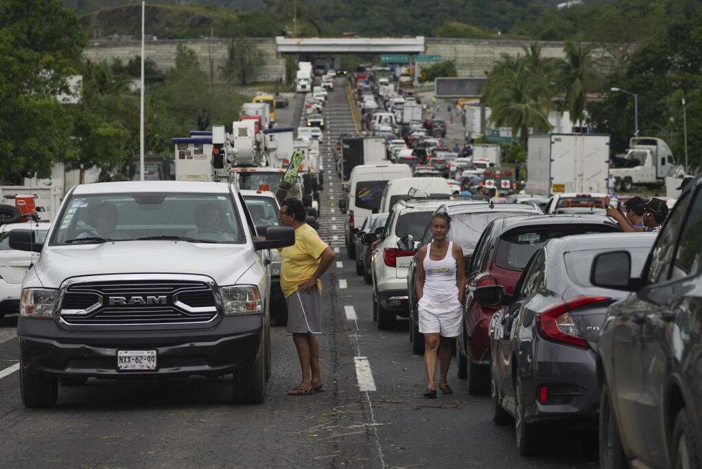 People wait outside their cars as they wait for repair crews to clear the roads after Hurricane Otis ripped through Acapulco, Mexico, Wednesday, Oct. 25, 2023. Hurricane Otis ripped through Mexico's southern Pacific coast as a powerful Category 5 storm, unleashing massive flooding, ravaging roads and leaving large swaths of the southwestern state of Guerrero without power or cellphone service. (AP Photo/Marco Ugarte)
