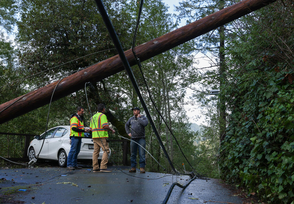 Resident Amber Godden right, talks with Sonoma County Director of Public Infrastructure Johannes Hoevertsz, and Road Operations Manager Rob Houweling along Summerhome Park Road, where utility lines downed by a tree block the roadway, in Forestville, Monday, Feb. 5, 2024.  (Christopher Chung / The Press Democrat)