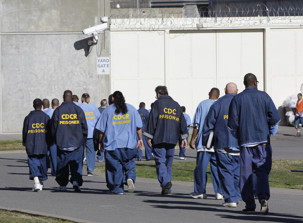 FILE - Inmates walk through the exercise yard at California State Prison Sacramento, near Folsom, Calif., on Feb. 26, 2013. Former California correctional officer Arturo Pacheco, who was fired from his job in 2018, pleaded guilty Monday, July 25, 2022, to federal charges stemming from two on-duty assaults in 2016. A second correctional officer who also was fired in 2018 previously pleaded guilty to submitting a false report about Pacheco's actions. Both officers worked at California State Prison, Sacramento, which neighbors Folsom State Prison east of Sacramento.  (AP Photo/Rich Pedroncelli, File)