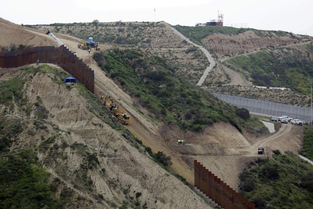 FILE - In this March 11, 2019 photo, construction crews replace a section of the primary wall separating San Diego, above right, and Tijuana, Mexico, below left, seen from Tijuana, Mexico. Defense Secretary Mark Esper has approved the use of $3.6 billion in funding from military construction projects to build 175 miles of President Donald Trump‚Äôs wall along the Mexican border. (AP Photo/Gregory Bull, File)