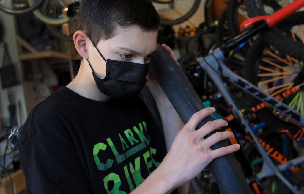 Clark Howe, 15, checks for an air leak in a bicycle tube off a  mountain bike that he is fixing at his home in Santa Rosa's Coffey Park community, Monday, Dec. 28, 2020.  (Kent Porter / The Press Democrat) 2020