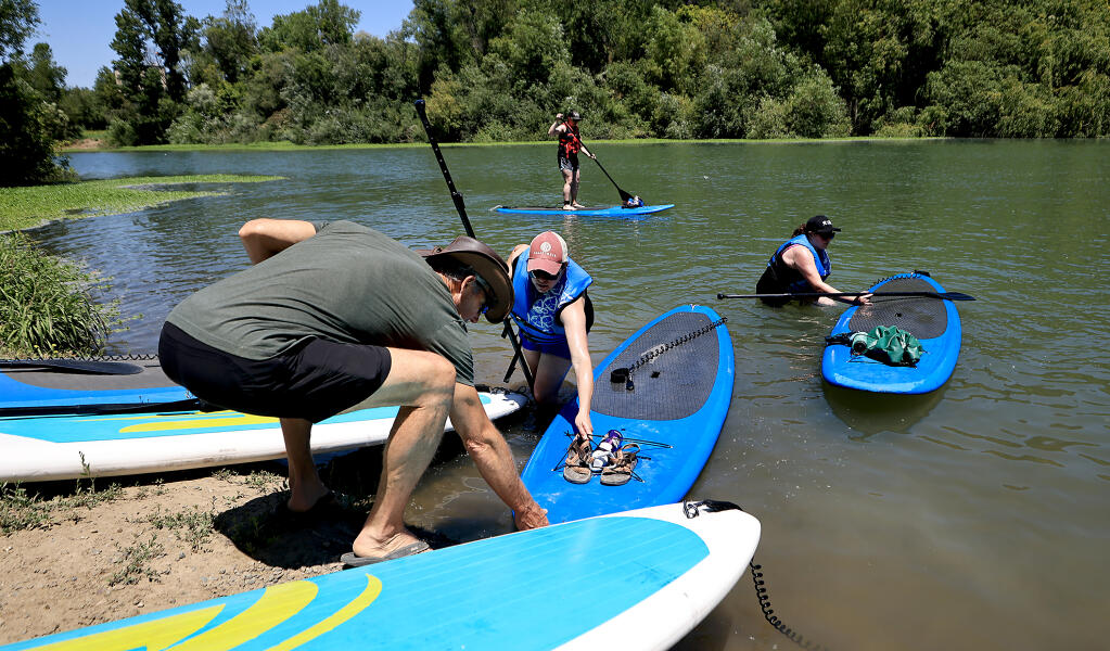 John Menth owner of Russian River Paddle Boards, guides Sahsa Browning, Sonja Rash and Sarah Bridges , all of Tacoma, in to shore during Menth's latest charter group to ply the Russian River at Wohler Bridge in Forestville, Thursday, June 29, 2023. (Kent Porter / The Press Democrat)