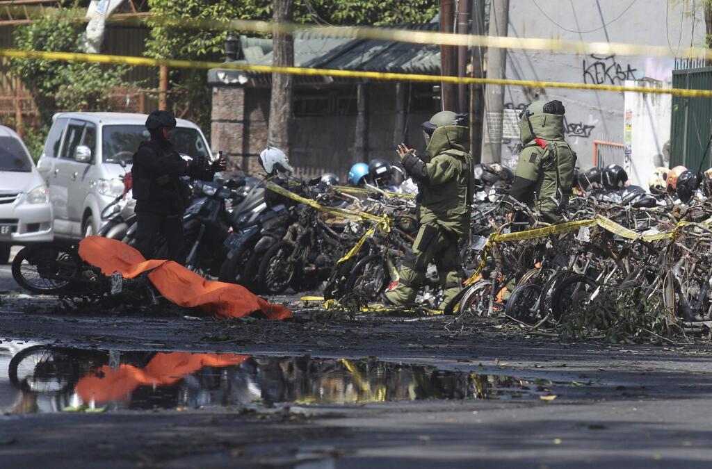 Members of police bomb squad inspect wreckage of motorcycles at the site where an explosion went off outside a church in Surabaya, East Java, Indonesia, Sunday, May 13, 2018. Almost simultaneous attacks including one by a suicide bomber disguised as a churchgoer targeted churches in Indonesia's second largest city of Surabaya early Sunday, killing a number of people and wounding dozens, police said. (AP Photo/Trisnadi)