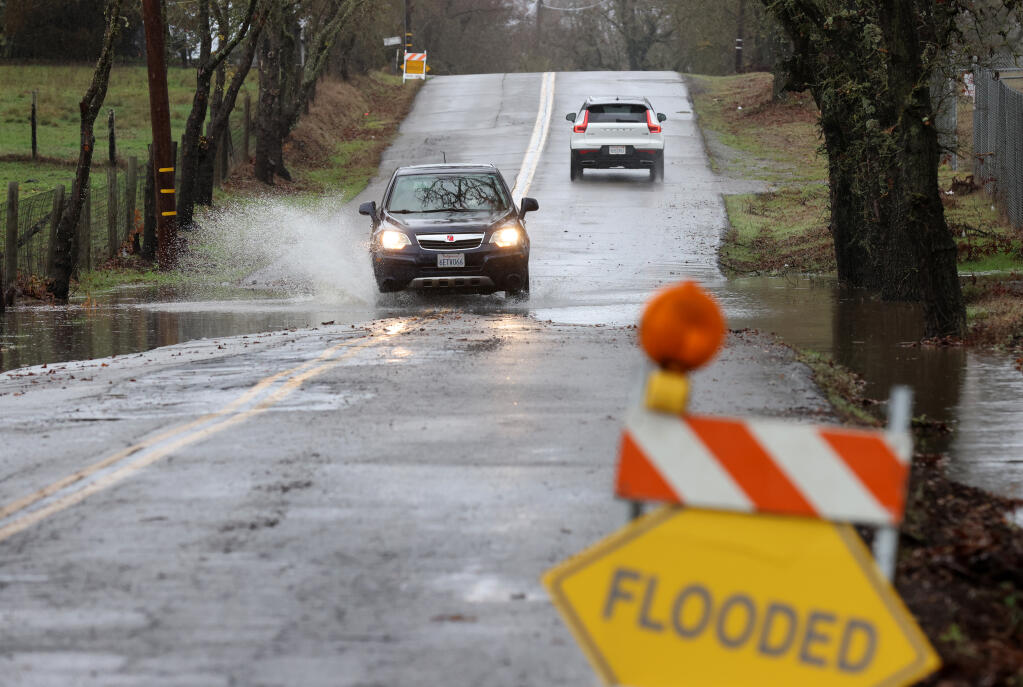 Vehicles drive through flood water on Windsor Road in Windsor, Calif., Tuesday, Dec. 27, 2022. (Beth Schlanker/The Press Democrat)
