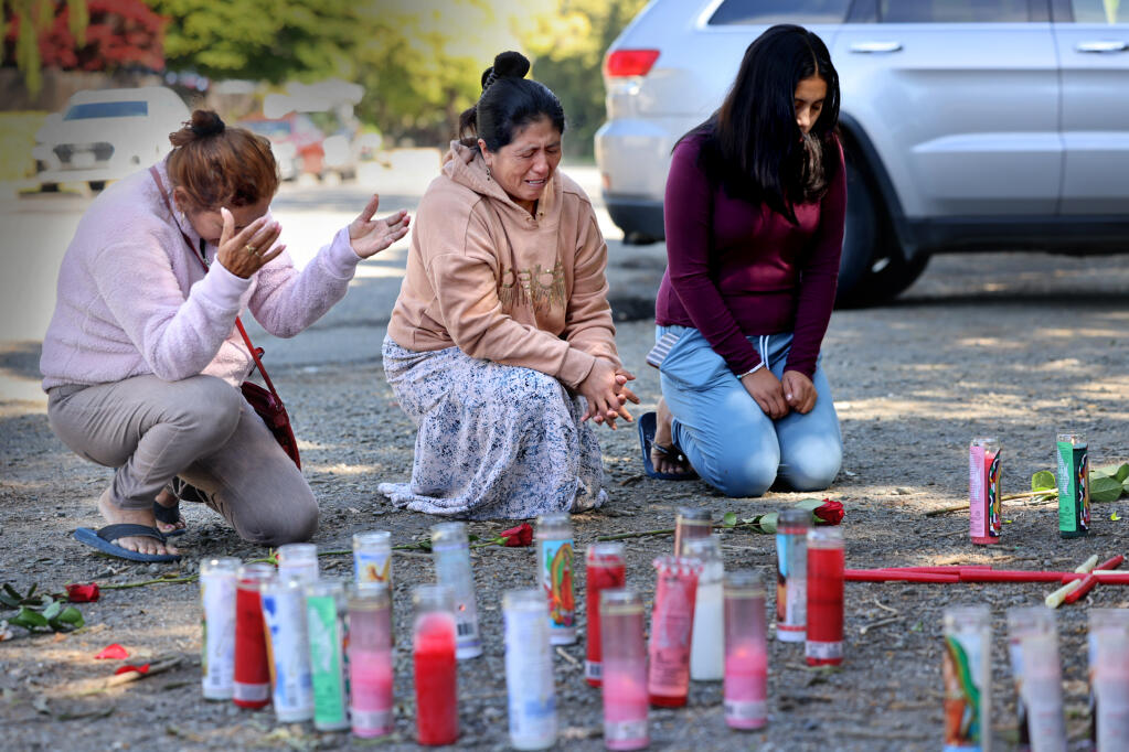 (From left) Noelia Serrano, Ilda Choc and her niece Angelica Choc pray near the site on Riverside Drive where a 17-year-old girl and 19-year-old woman were found fatally shot Sunday. Photo taken in Napa, Tuesday, April 16, 2024. (Beth Schlanker / The Press Democrat)
