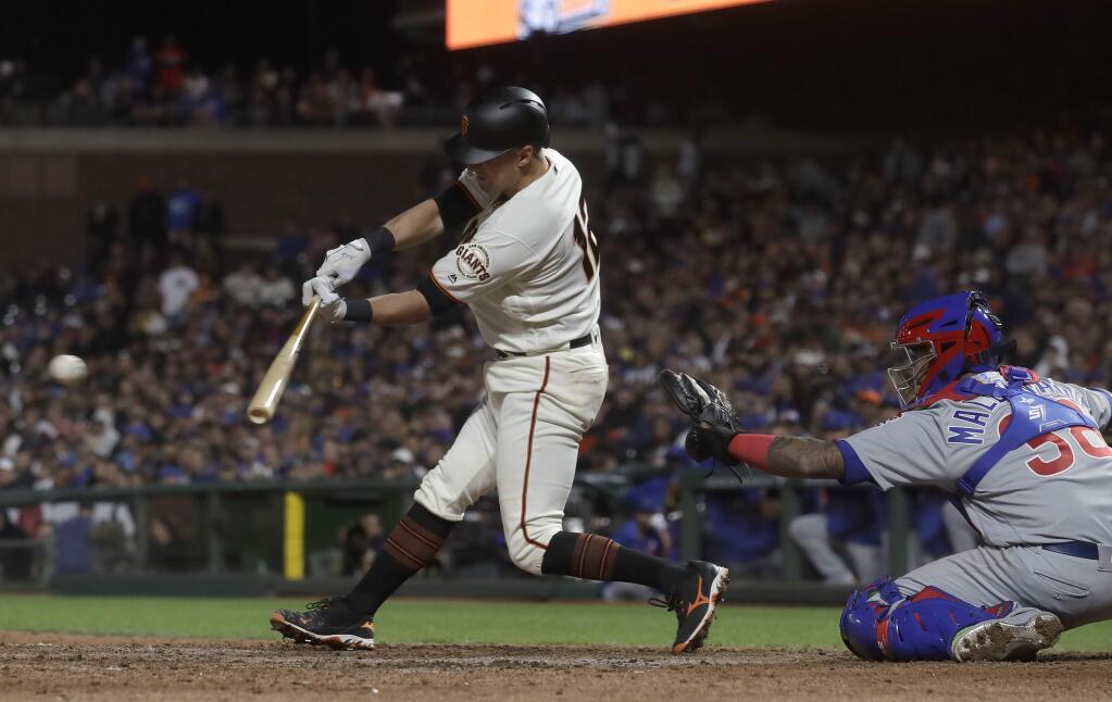 San Francisco Giants' Joe Panik, left, hits an RBI-double in front of Chicago Cubs catcher Martin Maldonado during the eighth inning of a baseball game in San Francisco, Monday, July 22, 2019. (AP Photo/Jeff Chiu)