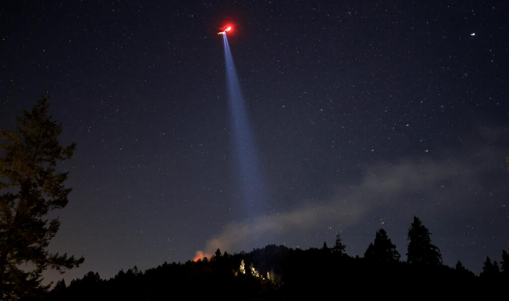 Personnel aboard Sonoma County Sheriff's Henry 1 helicopter use a spotlight to lead Monte Rio and Cal Fire firefighters in to the Terrace fire, Thursday, Feb. 10, 2022. Initial reports after crews gained access put the fire at about one acre. (Kent Porter / The Press Democrat)