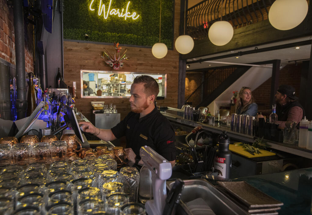 Rojo Bautista, bartender at Warike Restobar, closes out a guest check during lunch at the downtown Santa Rosa eatery on 4th Street Tuesday Feb. 22, 2022. (Chad Surmick / The Press Democrat)