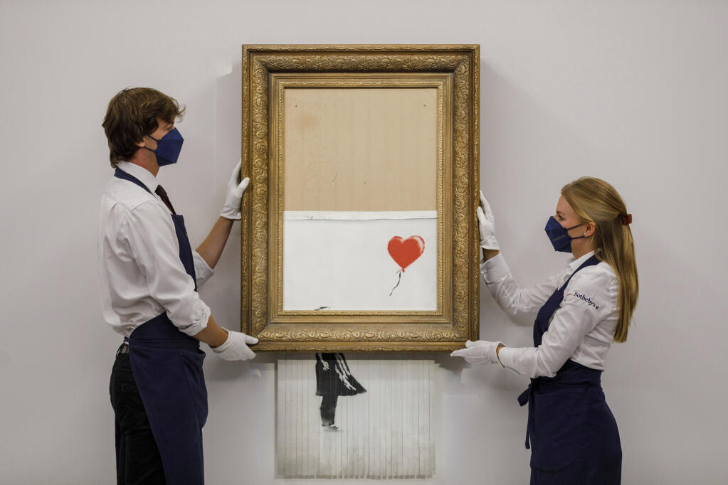 In this handout photo provided by Sotheby's Auction House, the auction for Banksy's "Love is the Bin" takes place in London, Thursday, Oct. 14, 2021. (Sotheby's Auction House via AP)