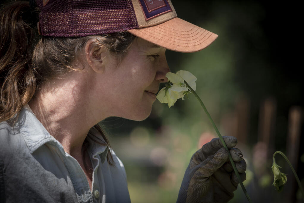 Farmer Maggie La Rochelle takes a moment to luxuriate in the scent of a flower at Sunray Farm on Arnold Drive on Thursday, June 1, 2023. (Robbi Pengelly/Index-Tribune)