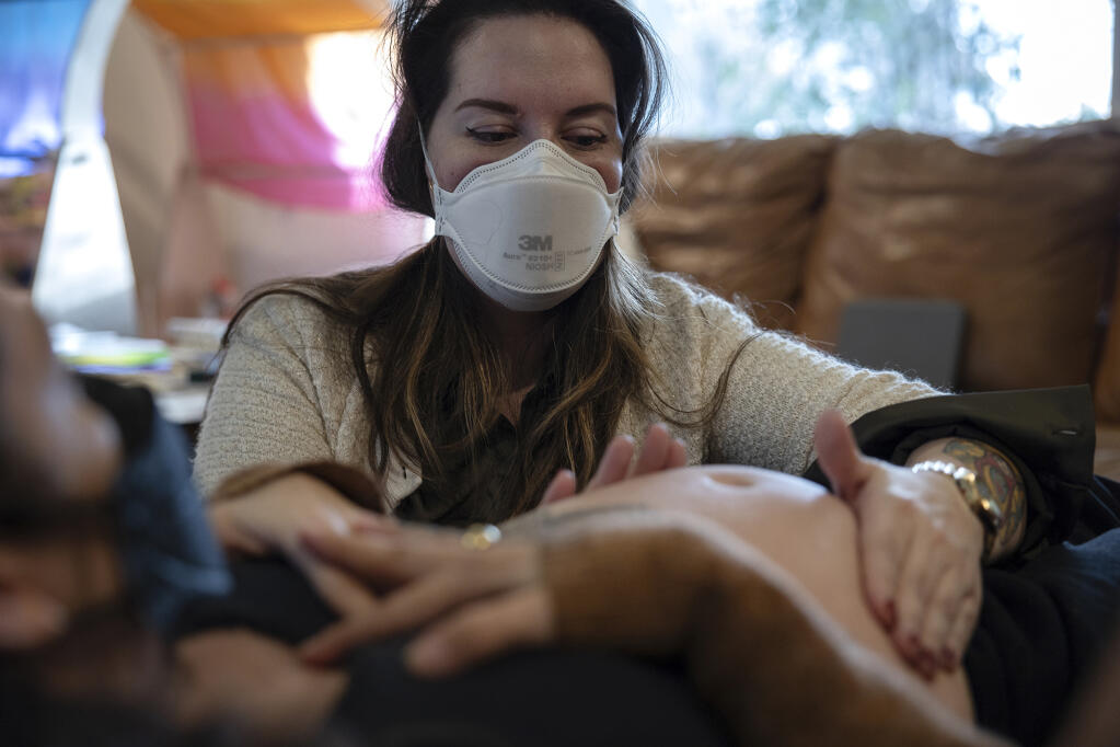 Midwife Madeleine Wisner evaluates Chloé Mick's belly during a maternal care consultation at Mick's home in Sacramento on Feb. 6, 2024. Photo by Miguel Gutierrez Jr., CalMatters