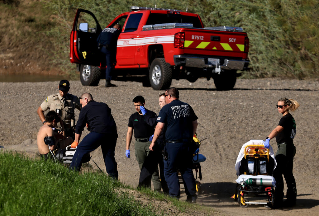 Sonoma County Fire District personnel tend to a teen who was pulled to safety after being caught in the Russian River current at Steelhead Beach in Forestville, Thursday, April 11, 2024. Another teen is missing. (Kent Porter / The Press Democrat)