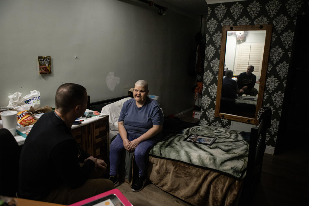 Physician assistant Brett Feldman and Calra Bolen sit in her room at a motel turned into housing for homeless residents as part of the state's Homekey program in downtown Los Angeles on Feb. 13, 2023. Photo by Larry Valenzuela for CalMatters/CatchLight Local