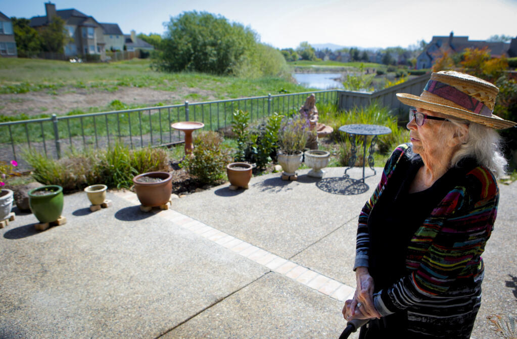 Alice Dransfield looks at overgrown grasses and weeds beyond her fenceline near the old Adobe Creek golf course in East Petaluma. She says the grass is a fire danger to her home. (CRISSY PASCUAL/ARGUS-COURIER STAFF)