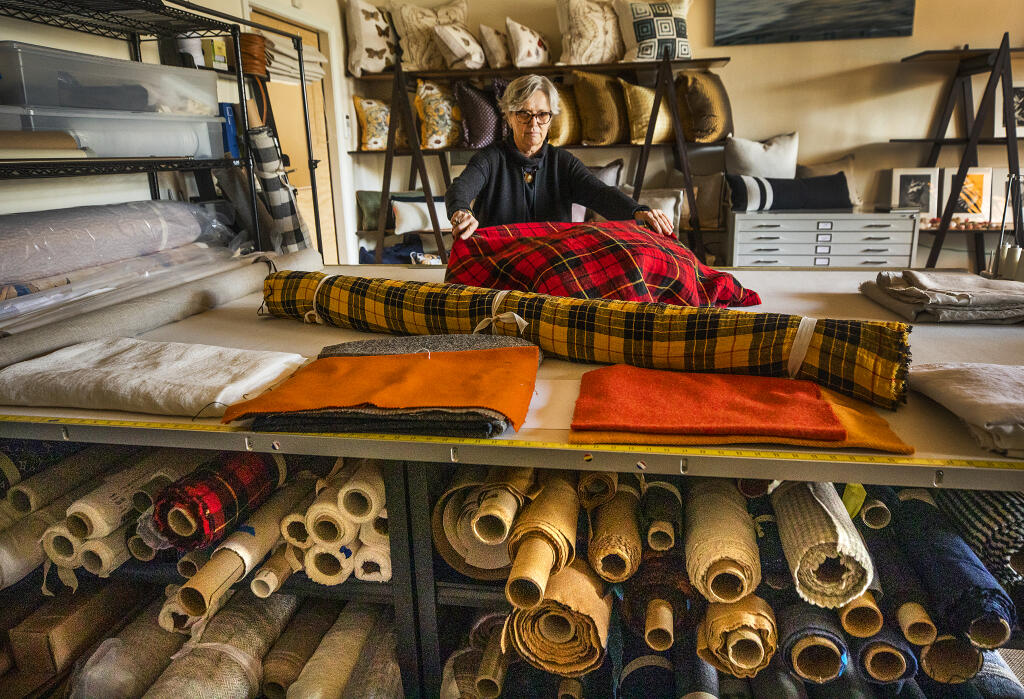 Dallas Saunders spreads out plaid cloth on her worktable on Friday, Oct. 22, 2021. Saunders, owner of Dallas A. Saunders Textiles & More, sells unique, upscale textiles online to designers. (John Burgess/The Press Democrat)