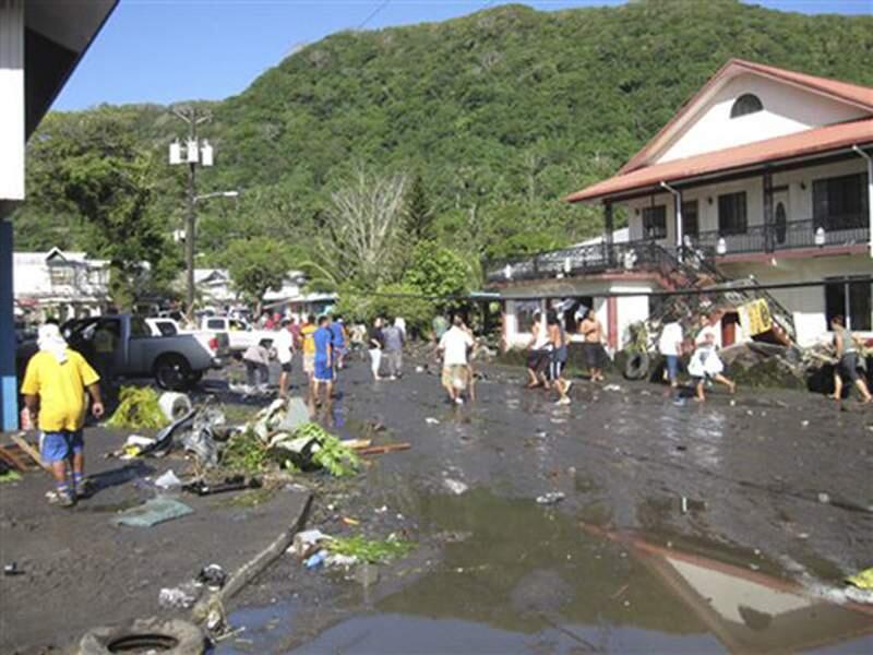 People walk through debris following a powerful quake, in Pago Pago village, on American Samoa Tuesday, Sept. 29, 2009. The quake in the South Pacific hurled massive tsunami waves at the shores of Samoa and American Samoa, flattening villages and sweeping cars and people back out to sea while leaving scores dead and dozens missing. (AP Photo/SamoaNews.com, Ausage Fausia)