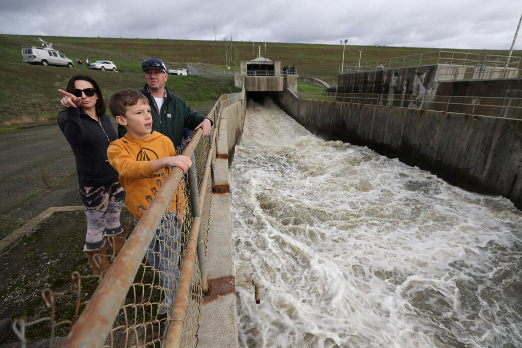 Mason Menton, 9, and family friends Jenny and Blane Costello watch Monday, Jan. 16, 2023, as water is released down the spillway at the Coyote Valley Dam at Lake Mendocino near Ukiah, Calif. (Beth Schlanker/The Press Democrat)