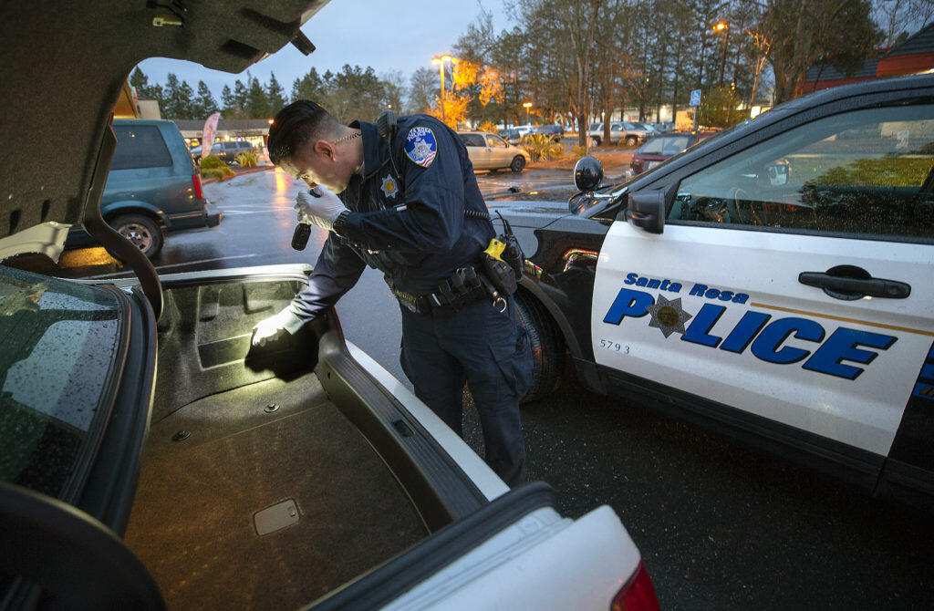 Santa Rosa police officer Noel Gaytan searches the car of a man suspected of driving with a suspended license in the Roseland Village Shopping Center on Monday, Feb. 11, 2019. (photo by John Burgess/The Press Democrat)