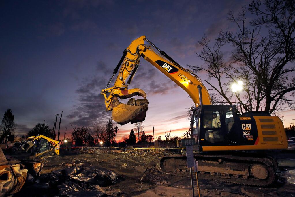An excavator crew from Ghilotti Construction Company works under artificial lights as they remove debris from a property in Coffey Park in Santa Rosa, California on Tuesday, November 28, 2017. (Alvin Jornada / The Press Democrat)
