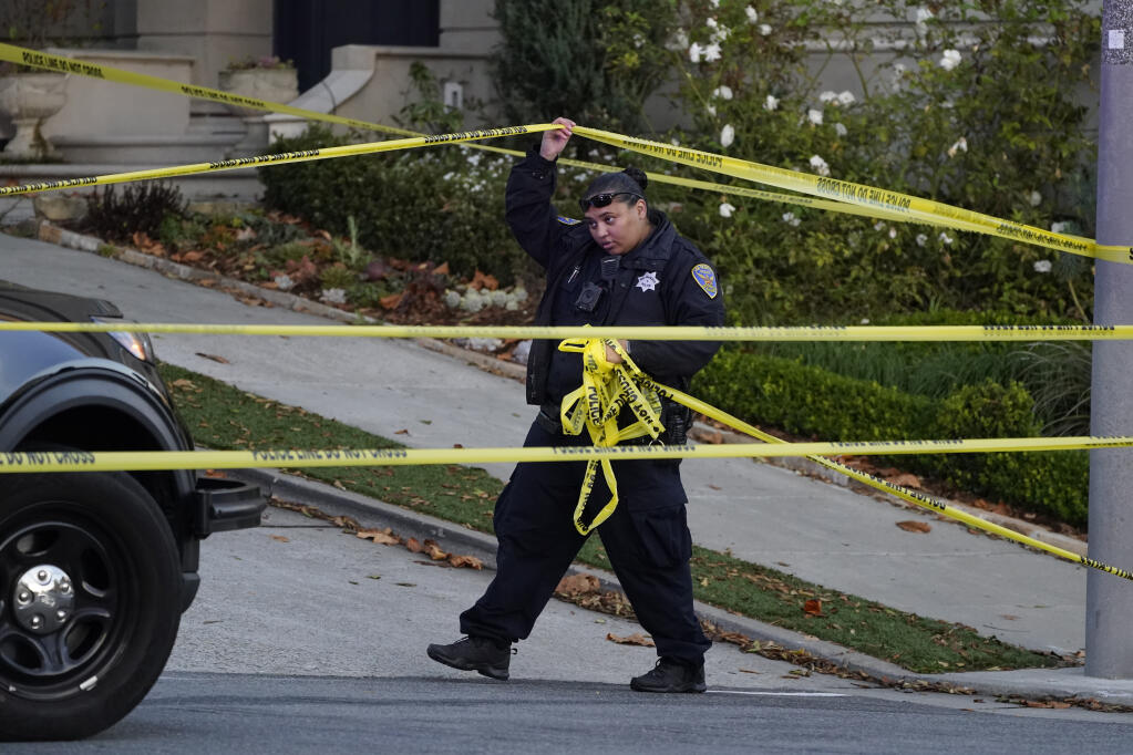 A police officer rolls out more yellow tape on the closed street below the home of Paul Pelosi, the husband of House Speaker Nancy Pelosi, in San Francisco, Friday, Oct. 28, 2022. Paul Pelosi, was attacked and severely beaten by an assailant with a hammer who broke into their San Francisco home early Friday, according to people familiar with the investigation. (AP Photo/Eric Risberg)