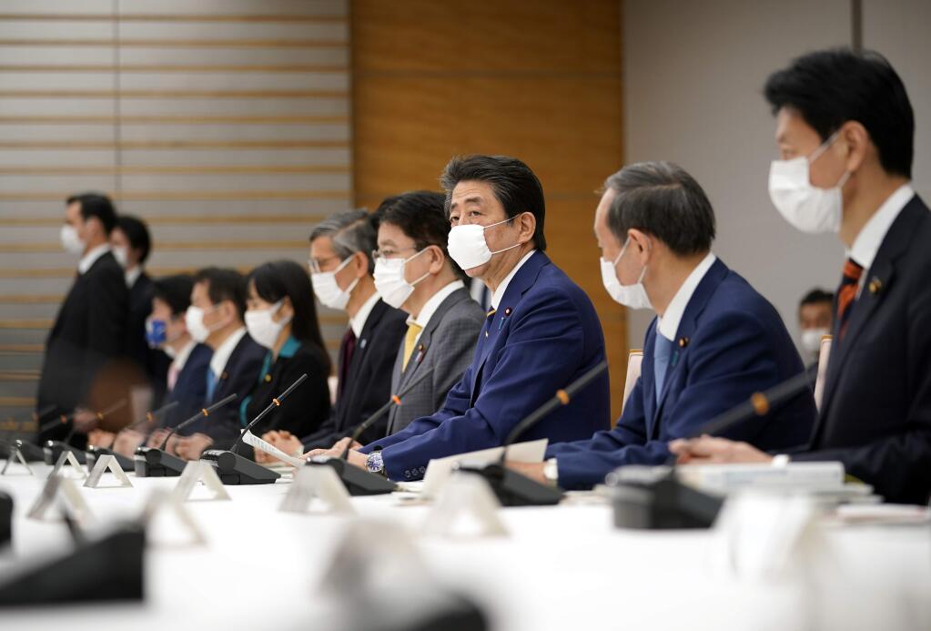 Japanese Prime Minister Shinzo Abe, center, declares a state of emergency during a meeting of the task force against the coronavirus at the his official residence in Tokyo, Tuesday, April 7, 2020. Abe declared a state of emergency for Tokyo and six other prefectures to ramp up defenses against the spread of the coronavirus. (Franck Robichon/Pool Photo via AP)